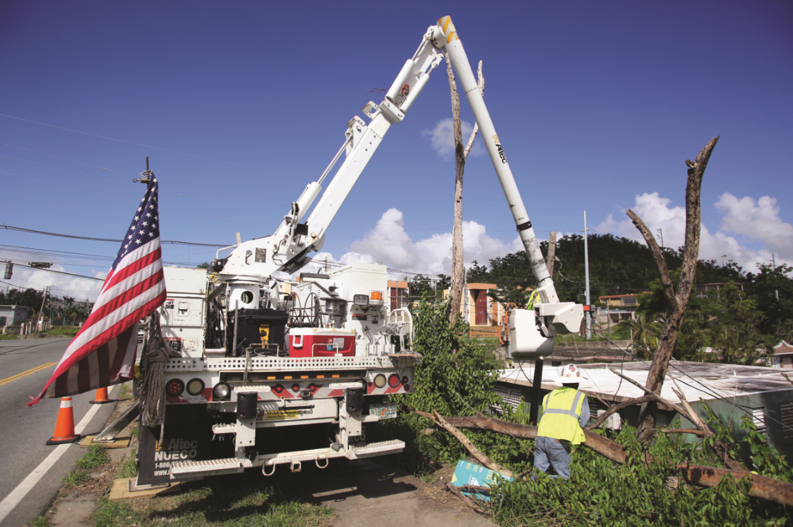 An electric utility crew from the mainland works on a line more than three months after Hurricane Maria cut it.
