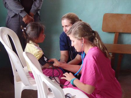 Morgan McClain '15 and professor Julie Ross with a young girl at the first clinic, in the San Francisco village outside Quito