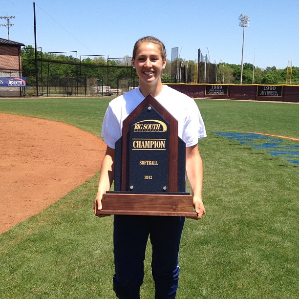 Softball players hold Big South Conference Champion placard/trophy