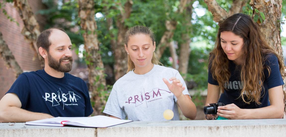 Rebecca Skelton ’18 drops a rubbery egg while Chelsea Dandridge ’17 photographs the experiment and physics professor Dr. Kenneth Pestka II Iooks on.