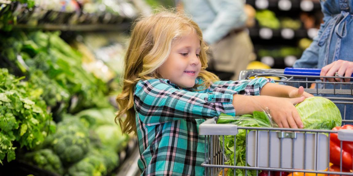 Little girl helping mother shop for produce in grocery store
