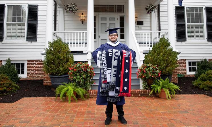 Bradley Phelps '20 stands in front of the Longwood House, proudly holding his collection of Longwood scarves, a unique tradition associated with The G.A.M.E. event each year.