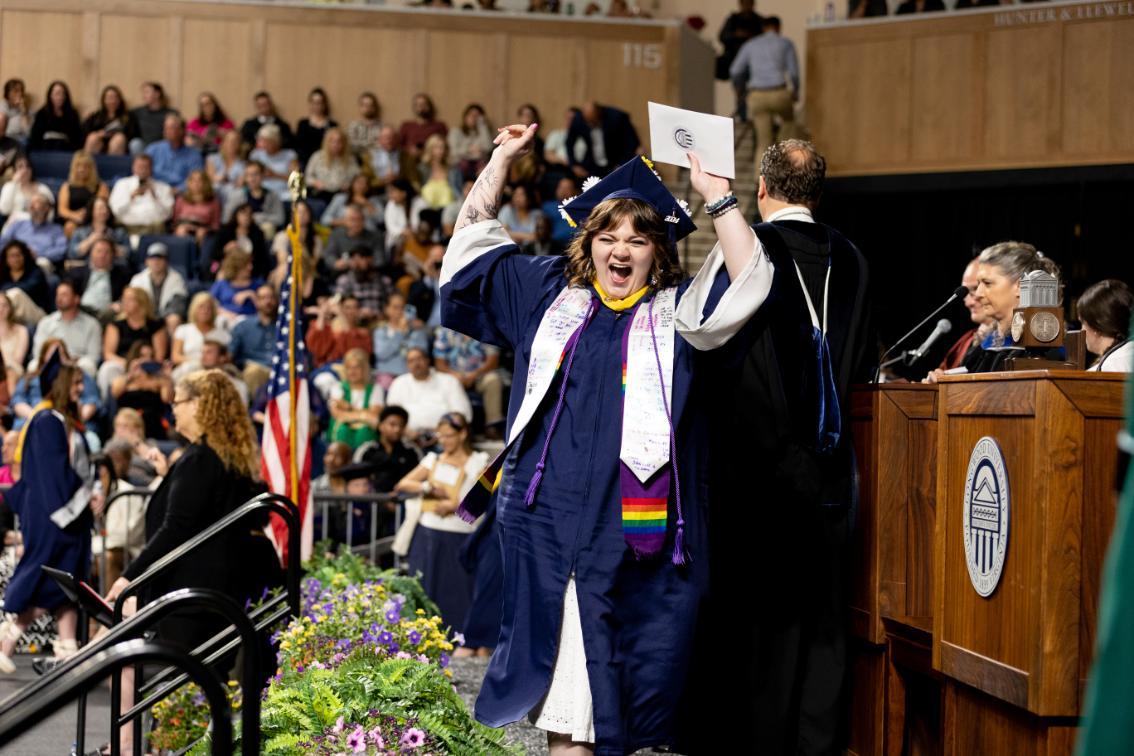 Undergraduate celebrates while crossing the stage