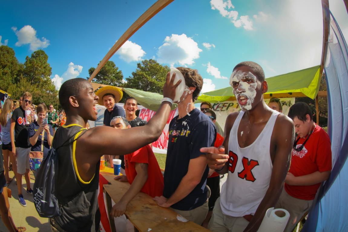 Longwood students wearing Greek letters get pies smashed in their face at a booth at Oktoberfest