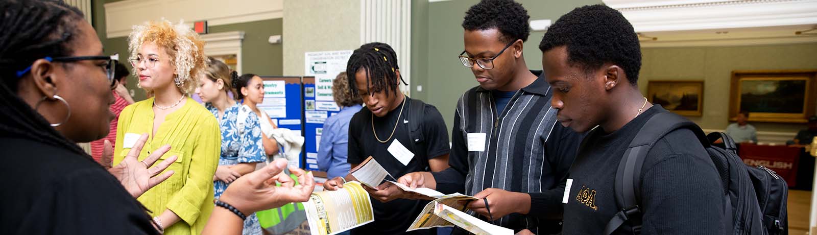 Students review career fair materials while speaking with an employer at a Longwood University career fair.