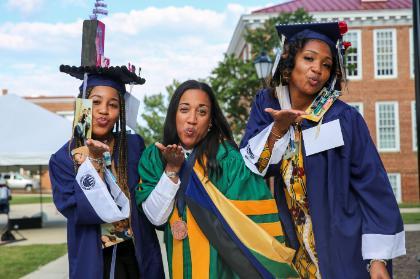 Dr. Meredith-Brown and two students blow kisses to the camera at Convocation. 