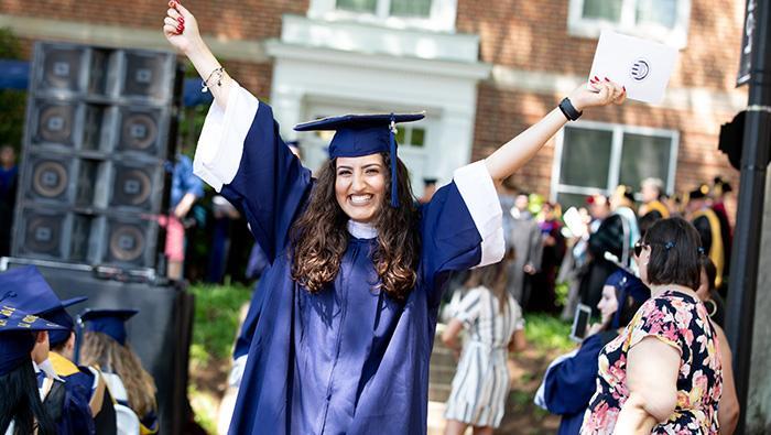 Student on commencement day with hands in the air celebrating