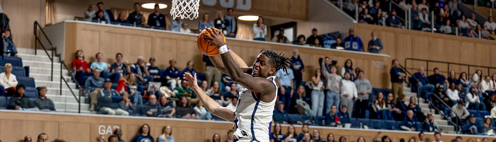 Longwood men’s basketball player reaches for a layup as fans watch from the stands in the Joan Perry Brock Center.