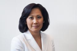 Headshot of Dr. Lisa Chen - A woman wearing a white blazer looks toward the camera with a calm expression. She has shoulder-length dark hair styled neatly around her face. The background is a plain, light-colored wall. Soft lighting highlights her features in a professional portrait.