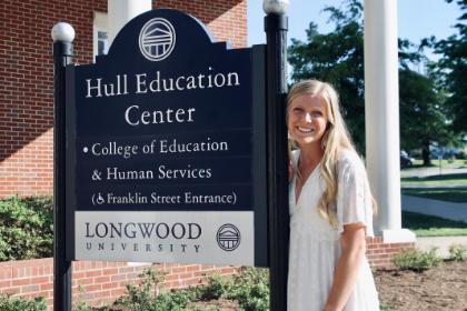 MaddieHommey stands next to the Hell Education Center sign. 