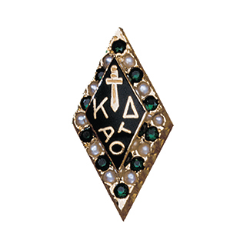 Kappa Delta pin - Gold Kappa Delta sorority pin in a diamond shape. Greek letters ΚΔ appear vertically in the center. Green stones and small pearls decorate the border. The pin is shown against a white background.