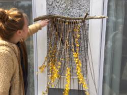 - A person stands outdoors examining a handmade wall hanging.