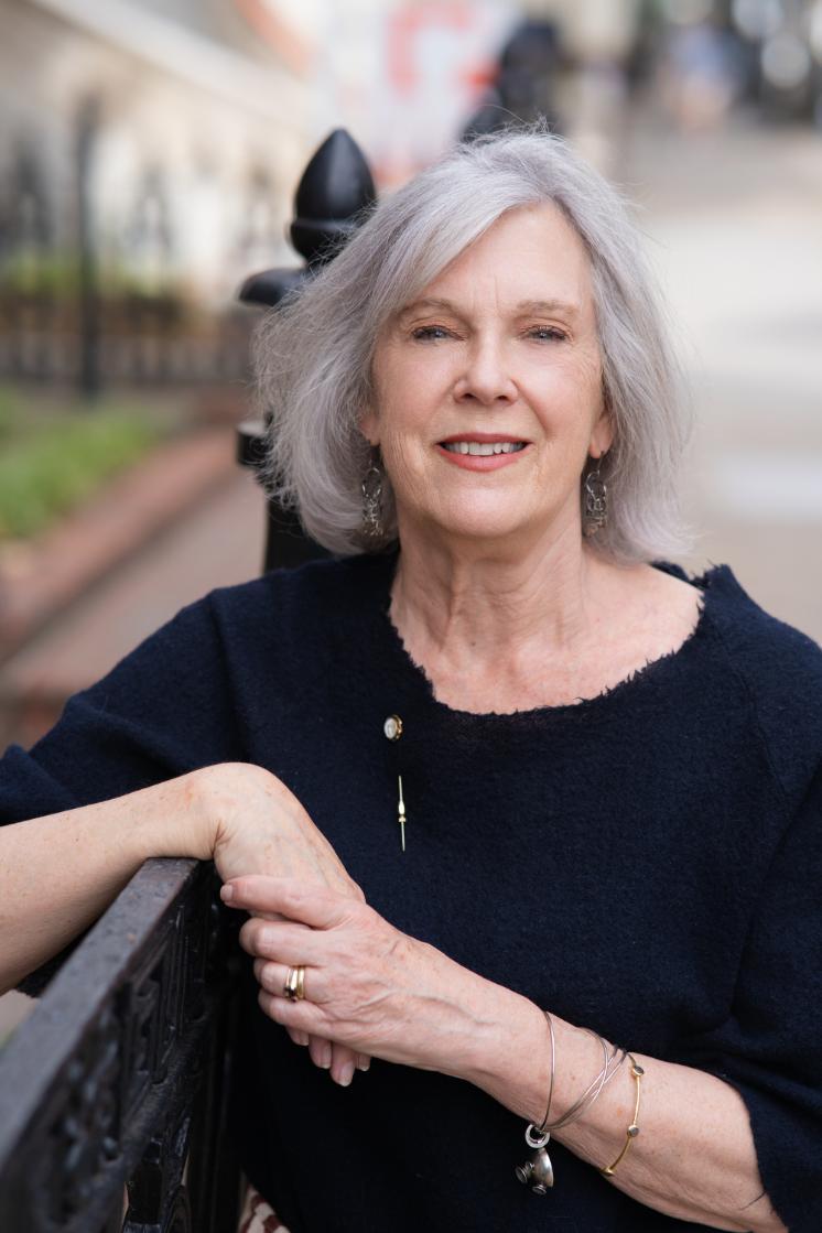 - A woman poses outdoors for a professional headshot.