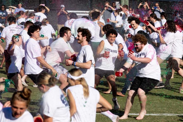Students in white Longwood shirts throw red and green paint during Color Wars