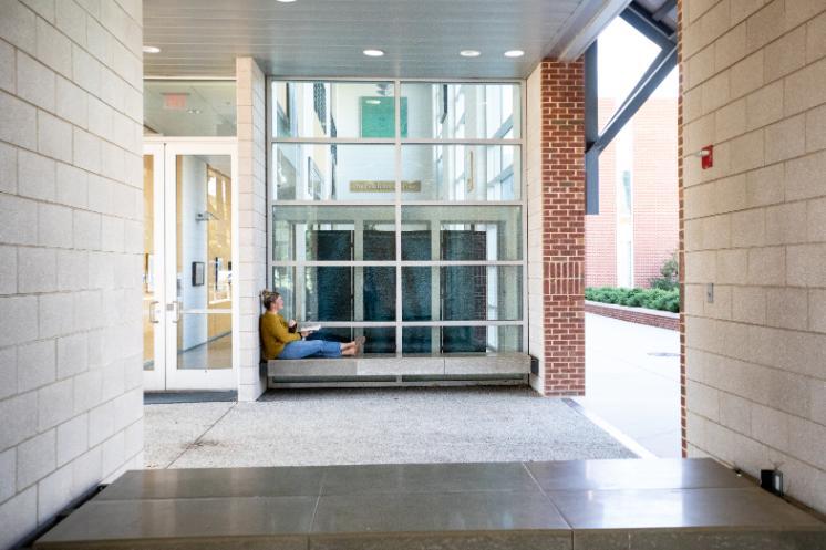 Student sitting in reading a book at the entrance 