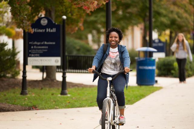 Student riding down Brock Commons on a bike