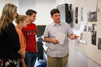 Students (left) Tatum Taylor, Maggie Dodson and Caleb Briggs confer with professor Michael Mergen about photo spreads in the magazine.
