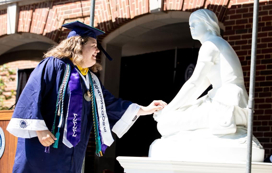 Student touching Joanie's hand while crossing the stage at commencement