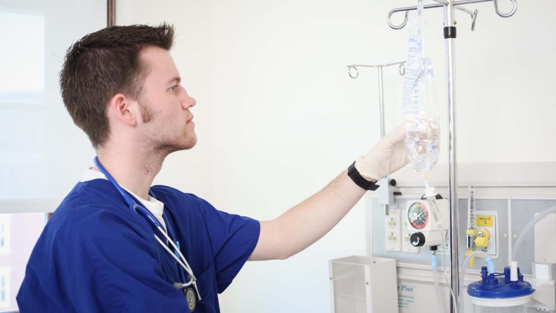 Nursing student checks an IV bag in the simulation lab