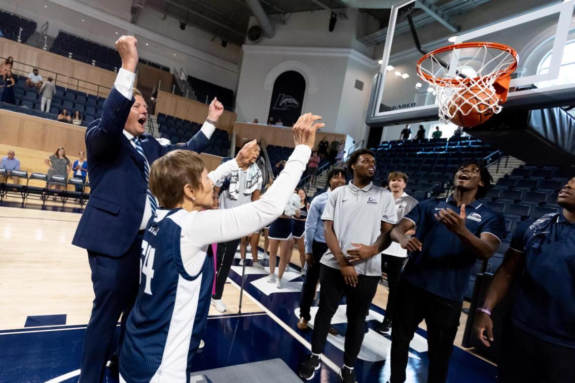 With President W. Taylor Reveley IV cheering her on, Joan Perry Brock '64 makes the first shot in the new Joan Perry Brock Center.