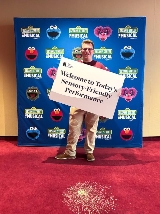 Aidan Brown '26 holds a sign welcoming guests to a sensory-friendly version of the night's performance at the Kennedy Center