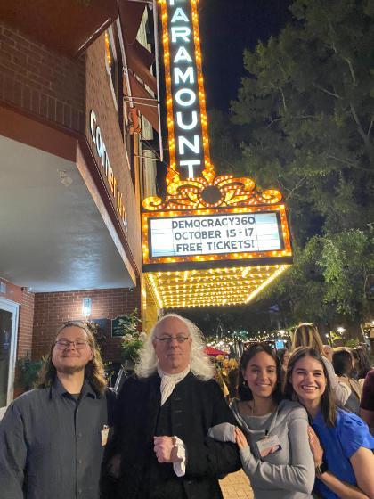 L to R: Ryan Childress ’26, Angie Scotece ’26 and Tori Labott ’26 pose with a period reenactor in front of the Paramount Theatre in Charlottesville.