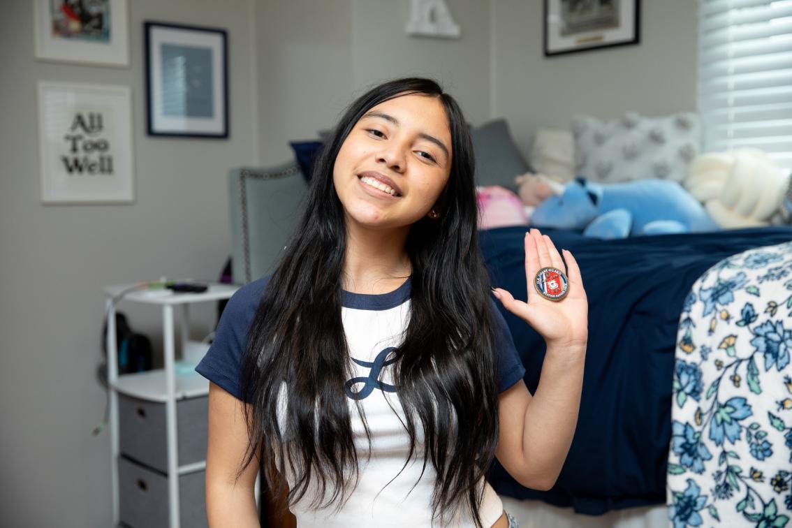 Angie Ramirez ’29 in her room in Moss Hall with the U.S. Coast Guard challenge coin her boyfriend gave her