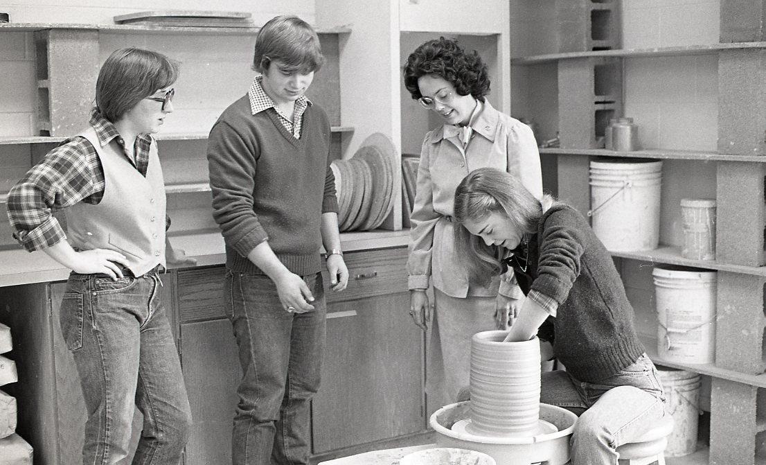Dr. Janet D. Greenwood (background) looks on as a student throws pottery on a wheel
