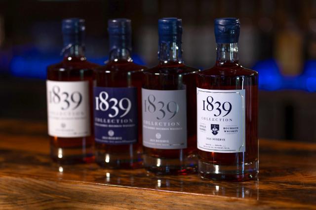 Four bottles of Longwood’s 1839 Collection bourbon whiskey are displayed on a wooden bar, including the 2026 Reserve bottle in front.